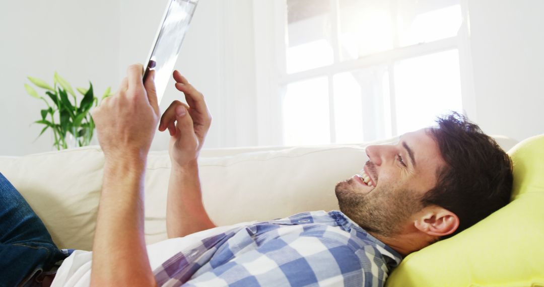 Man Relaxing at Home with Tablet, Smiling and Reading - Free Images, Stock Photos and Pictures on Pikwizard.com