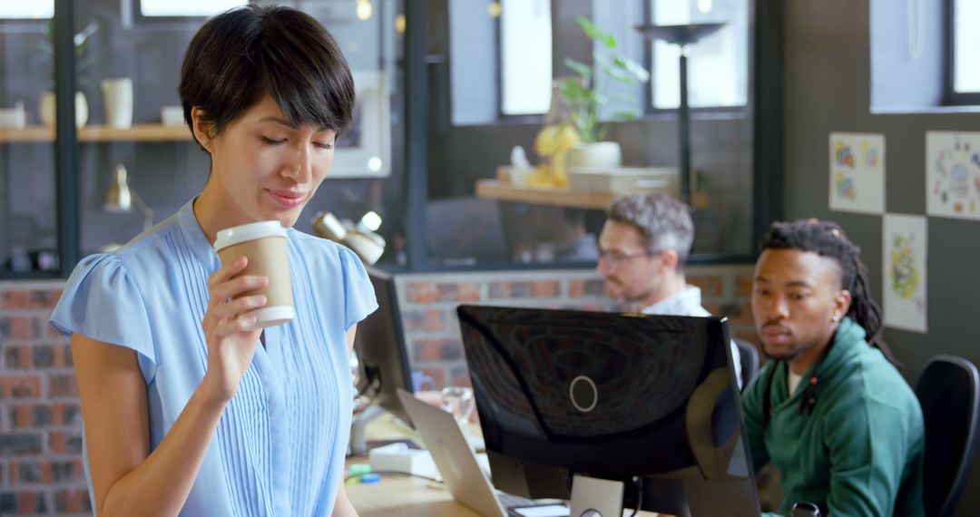 Businesswoman Enjoying Coffee in Modern Office with Diverse Coworkers - Free Images, Stock Photos and Pictures on Pikwizard.com