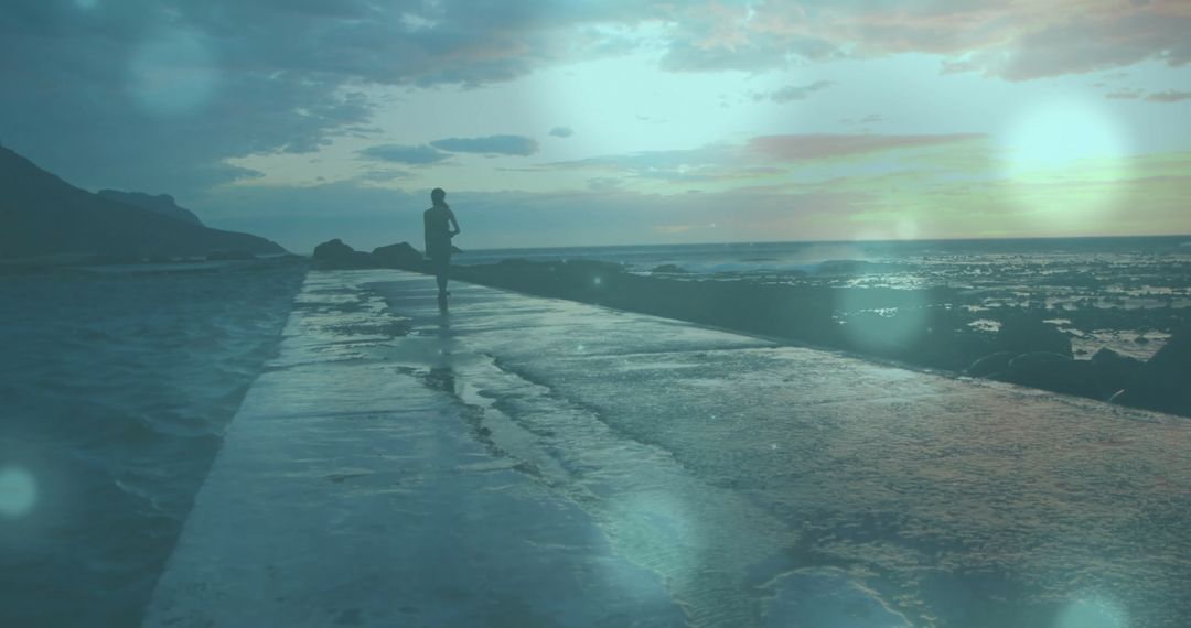 Silhouette of Jogger on Coastal Path at Sunrise with Artistic Light Flare