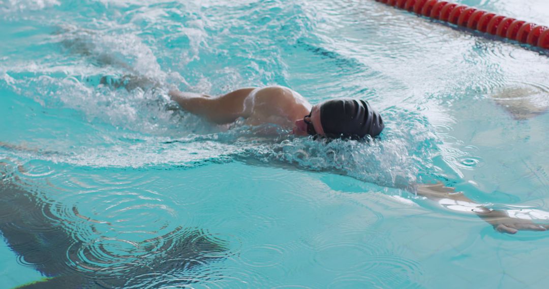 Male Swimmer Executing Crawl Stroke in Indoor Pool Lane