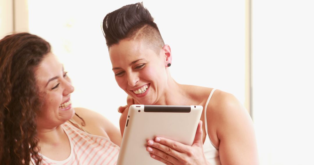 Two Women Smiling and Using Digital Tablet at Home - Free Images, Stock Photos and Pictures on Pikwizard.com