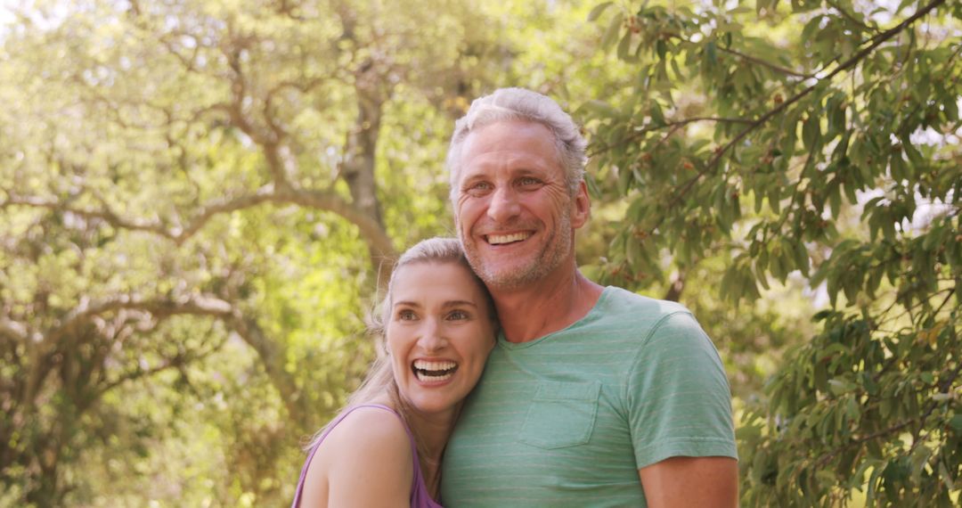 Smiling Middle-Aged Couple Embracing Outdoors in Sunlit Park - Free Images, Stock Photos and Pictures on Pikwizard.com