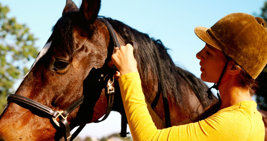 A young Caucasian woman wearing a riding helmet is affectionately grooming a horse, with copy space - Free Images, Stock Photos and Pictures on Pikwizard.com