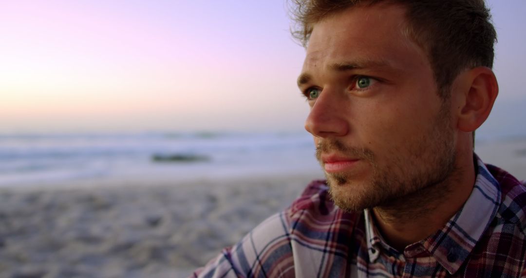 Thoughtful Young Man Relaxing on Beach During Sunset