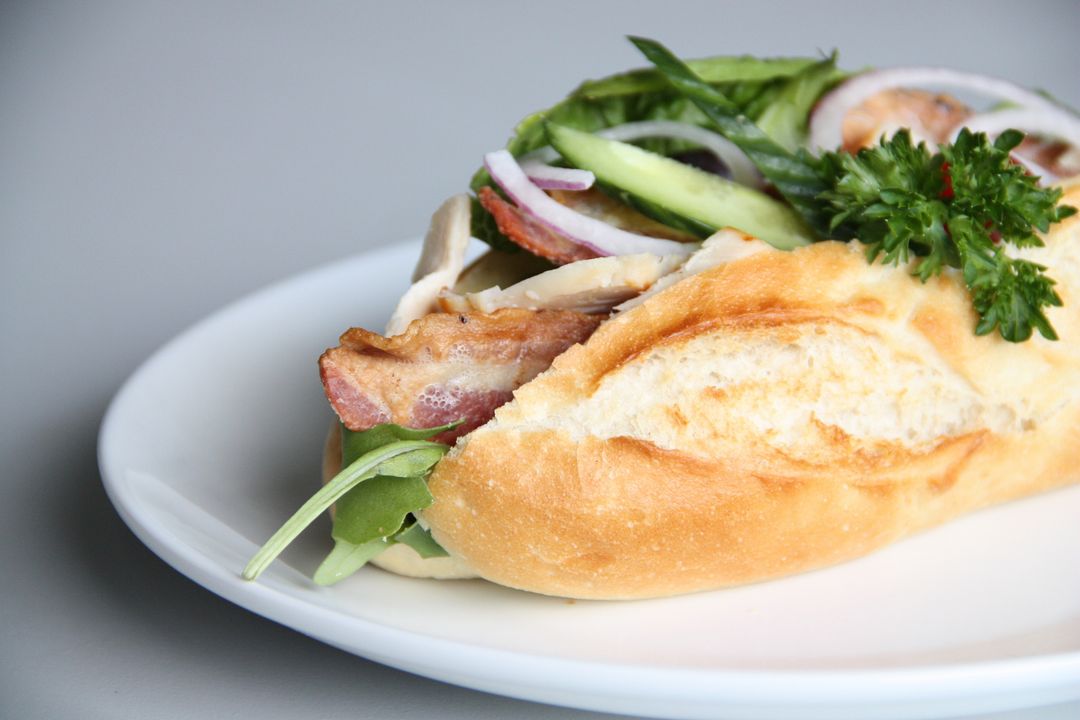 Crispy Bacon and Fresh Vegetable Baguette Sandwich Featuring Cucumber, Onion, Parsley