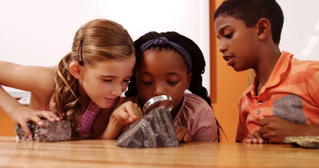 Diverse children examining rocks with magnifying glass in classroom setting - Free Images, Stock Photos and Pictures on Pikwizard.com