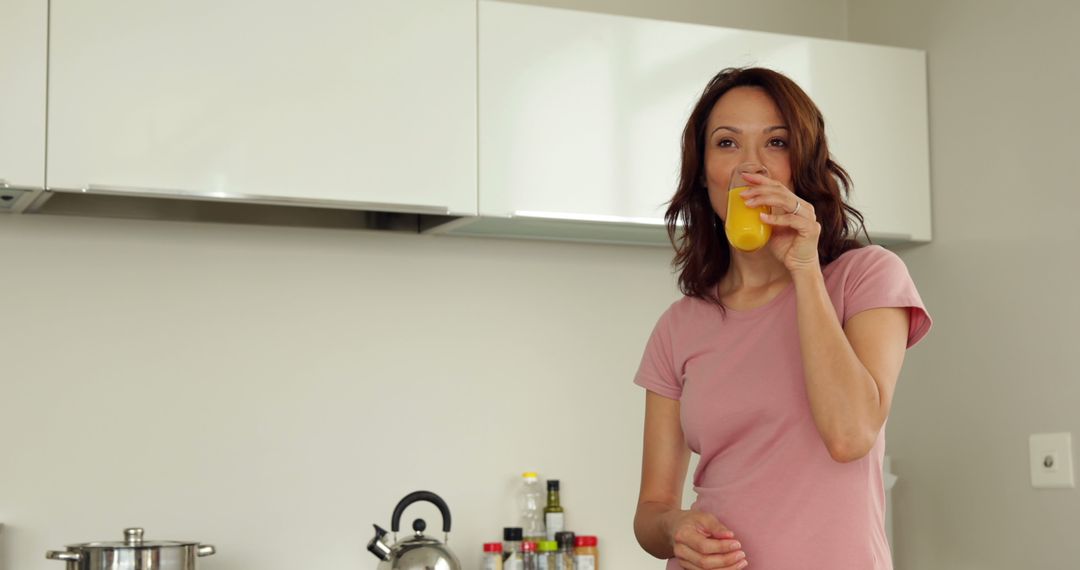 Woman Drinking Orange Juice in Modern Kitchen - Free Images, Stock Photos and Pictures on Pikwizard.com
