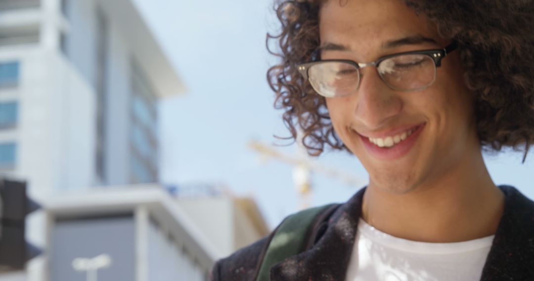 Smiling Young Man Walking Outdoors With Glasses and Curly Hair - Free Images, Stock Photos and Pictures on Pikwizard.com