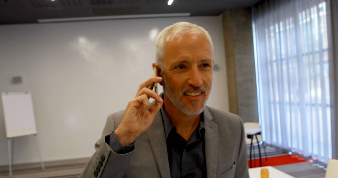 Businessman Engaged in a Phone Call in Modern Office Setup - Free Images, Stock Photos and Pictures on Pikwizard.com