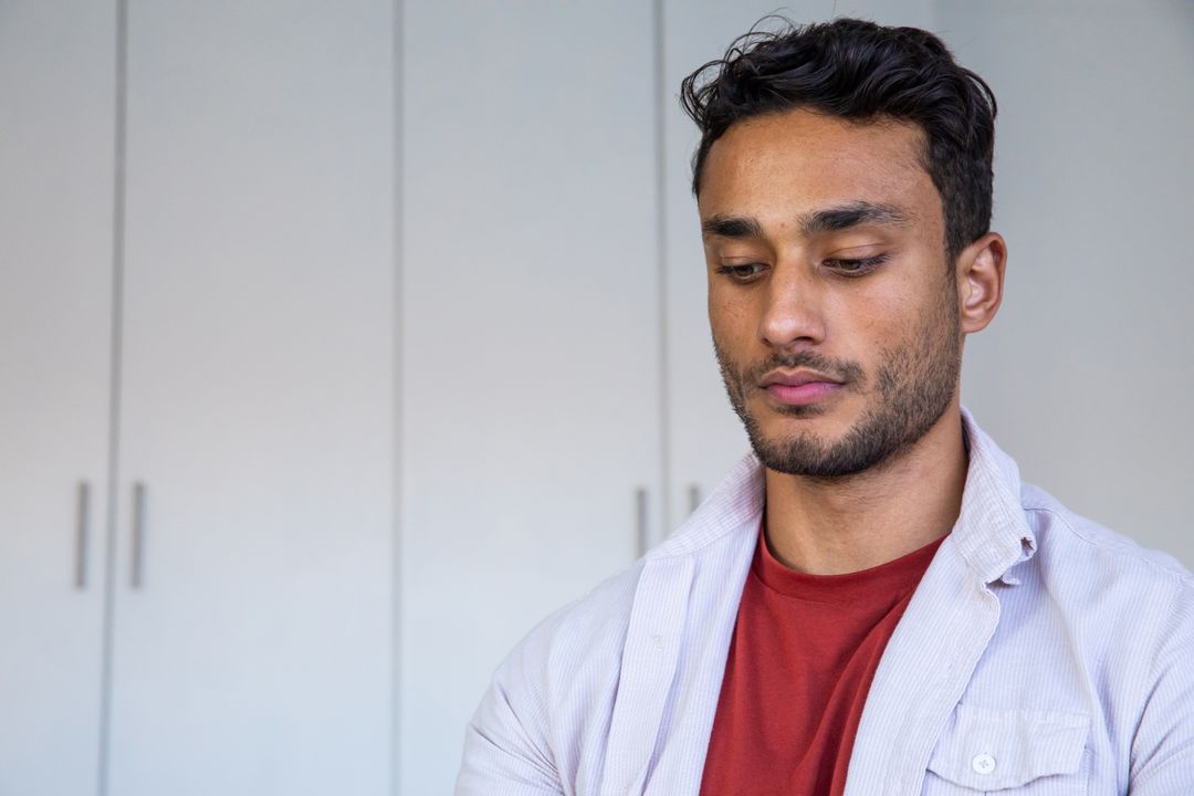 Contemplative Man in Casual Attire Inside Minimalist Room