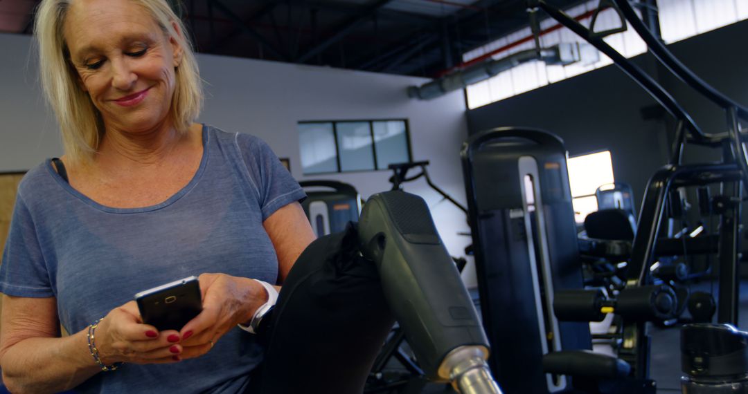 Older Woman with Leg Prosthetic Texting at Gym - Free Images, Stock Photos and Pictures on Pikwizard.com