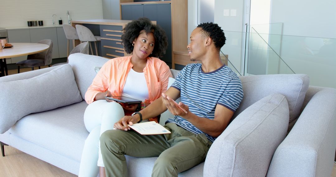 African American Couple Discussing Using Tablet on Sofa at Home