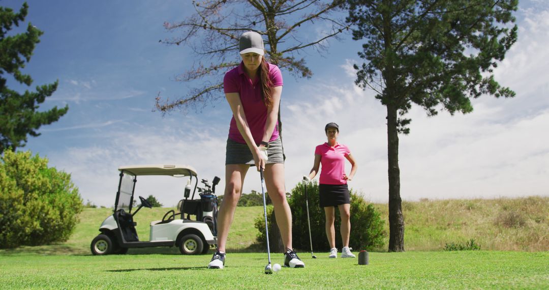 Two Women Golfers Preparing to Tee Off on Sunny Course - Free Images, Stock Photos and Pictures on Pikwizard.com