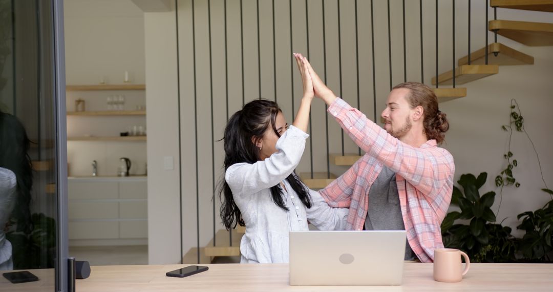Successful Couple High-Fiving Achievements with Joy at Home
