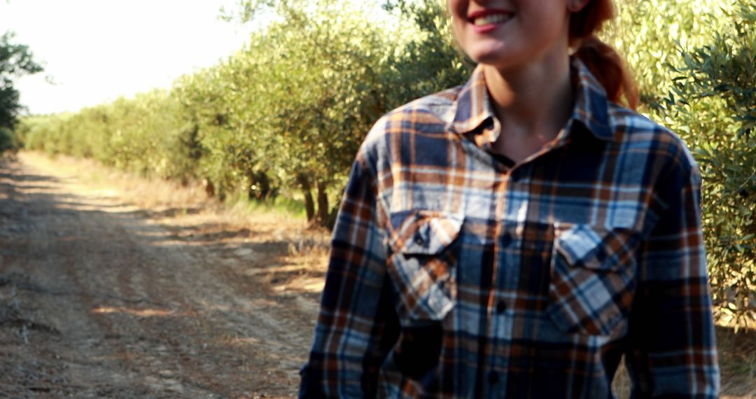 Young Woman Smiling in Plaid Shirt at Olive Grove - Free Images, Stock Photos and Pictures on Pikwizard.com