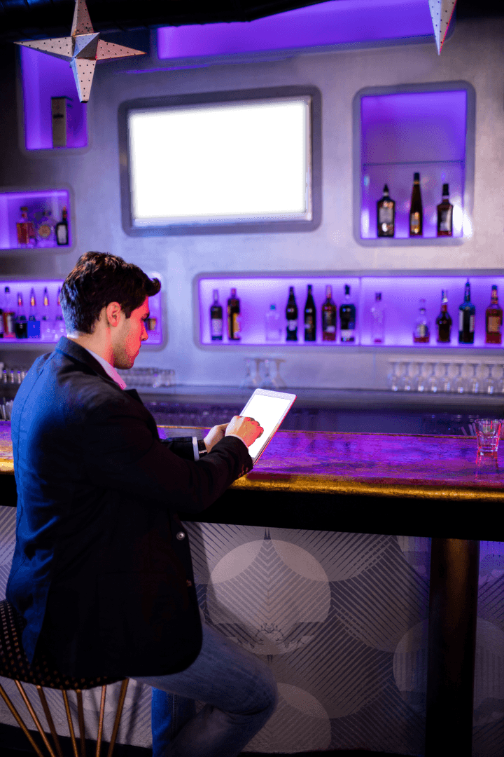 Businessman on Tablet at Sleek Bar with Vivid Lighting