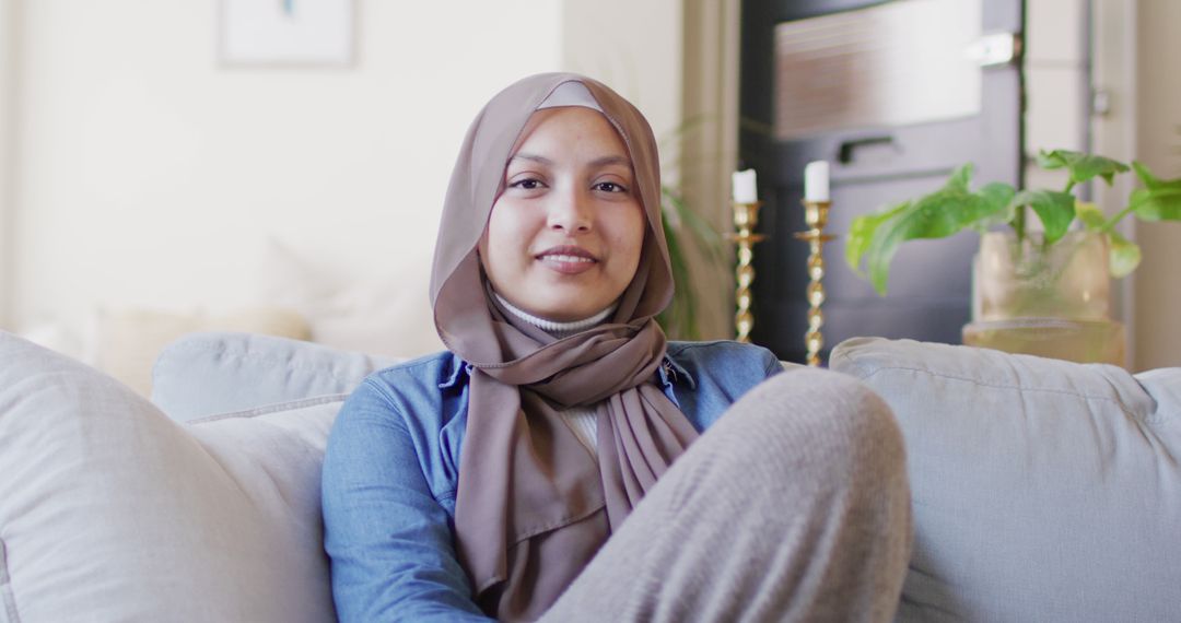 Smiling Woman in Hijab Sitting on Couch in Modern Cozy Living Room - Free Images, Stock Photos and Pictures on Pikwizard.com