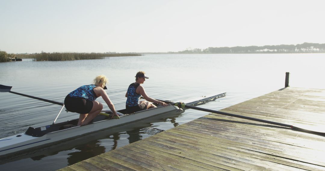 Two Rowers Preparing to Launch Boat on Serene Lake - Free Images, Stock Photos and Pictures on Pikwizard.com