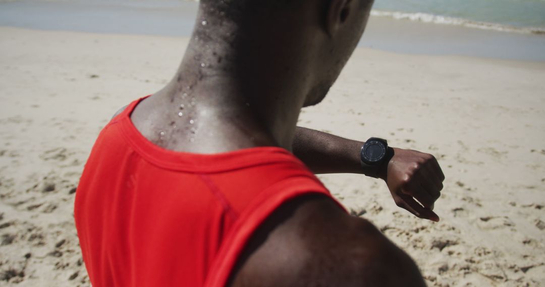 African American man on beach looking at smartwatch after a workout - Free Images, Stock Photos and Pictures on Pikwizard.com