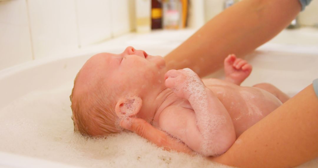 Parent Giving Newborn Baby A Bath In Bathtub With Soap Bubbles - Free Images, Stock Photos and Pictures on Pikwizard.com