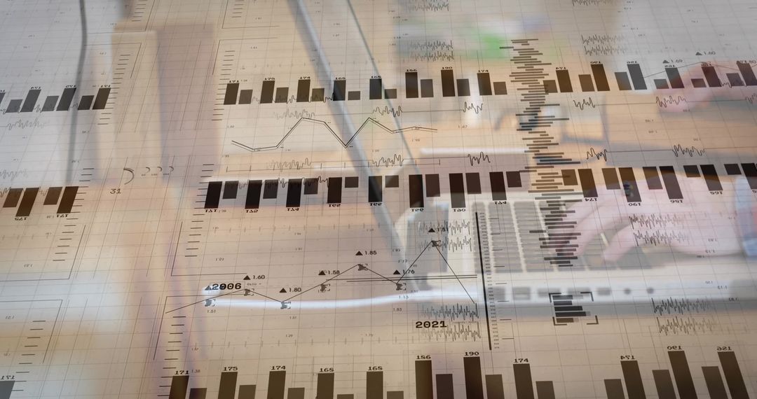 Analyst Working with Financial Charts and Laptop Overlay Showing Market Data Trends