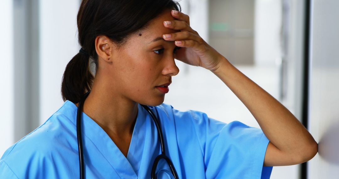 Stressed Healthcare Worker in Hospital Corridor - Free Images, Stock Photos and Pictures on Pikwizard.com