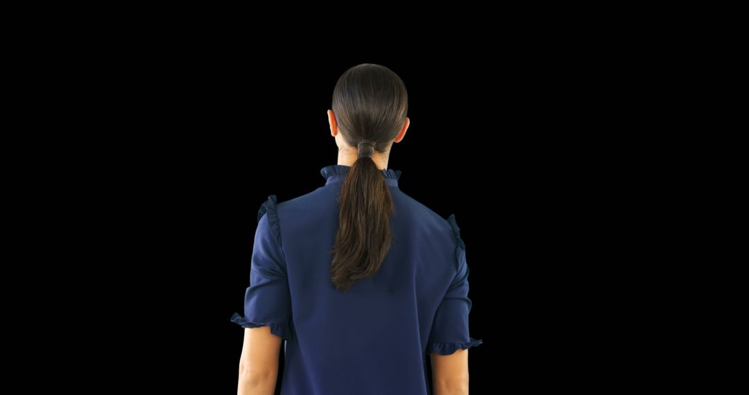 Rear View of Businesswoman Standing Against Dark Background