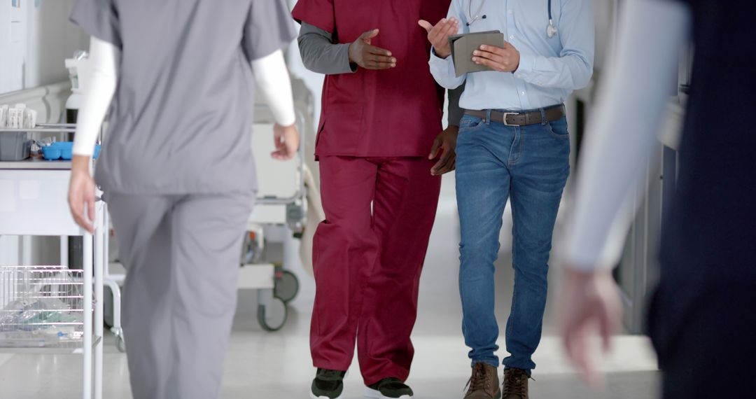 Healthcare Team Walking Through Hospital Corridor Discussing - Free Images, Stock Photos and Pictures on Pikwizard.com