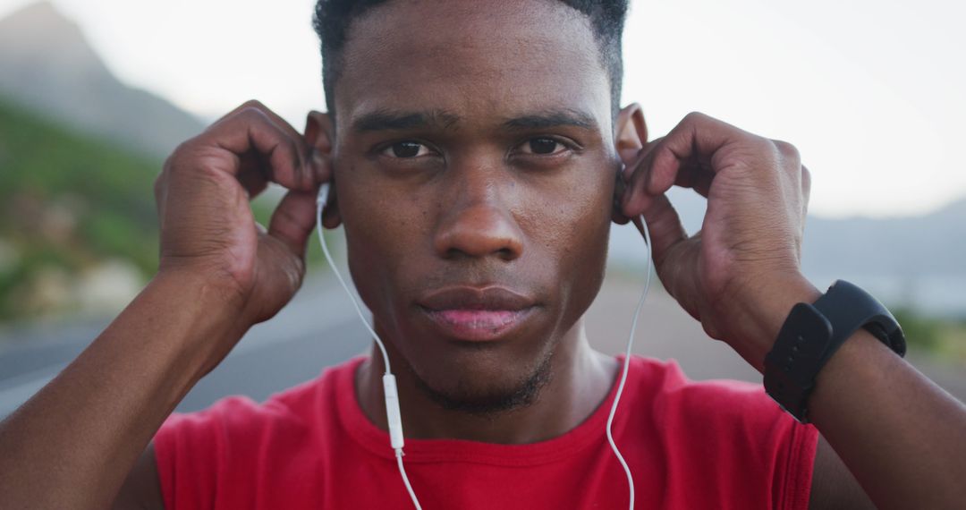 Focused African American Man Preparing for Run with Earphones Outdoors - Free Images, Stock Photos and Pictures on Pikwizard.com