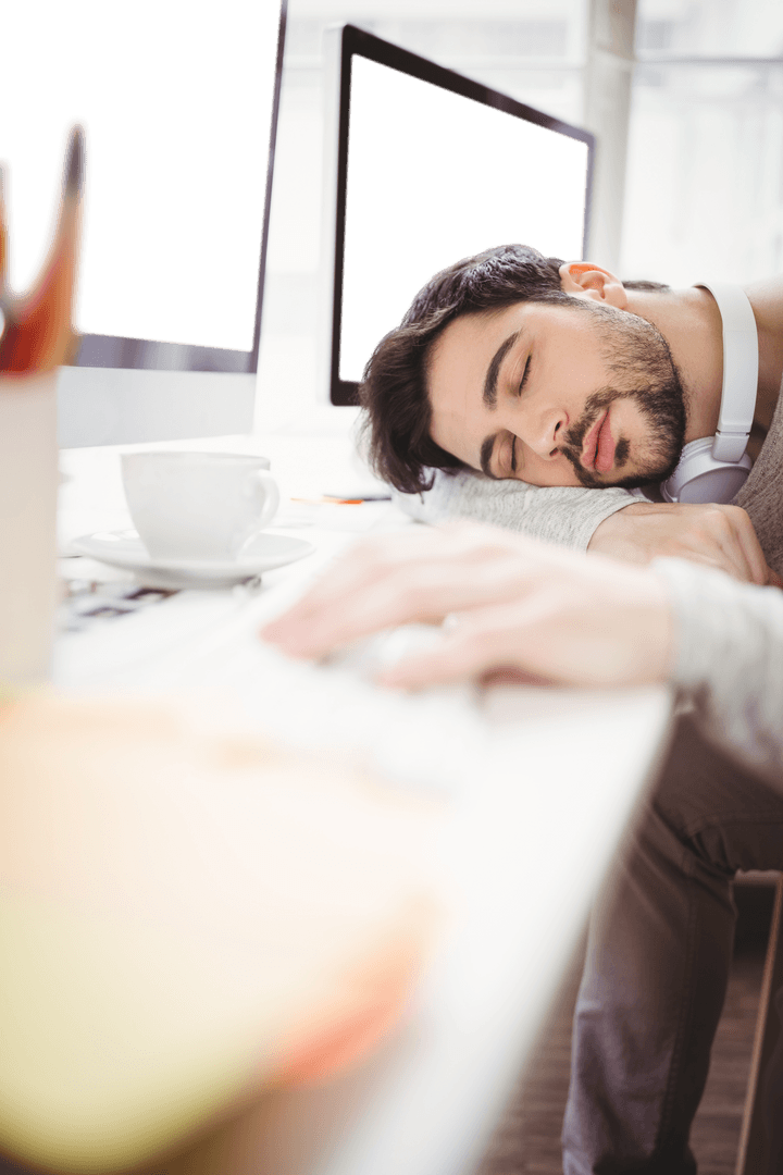 Exhausted Man Sleeping on Office Desk, Monitors Blank