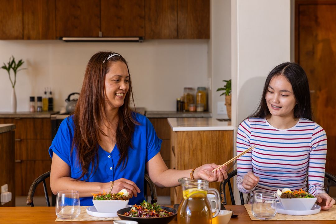 Mother and Daughter Sharing Mealtime with Chopsticks at Home