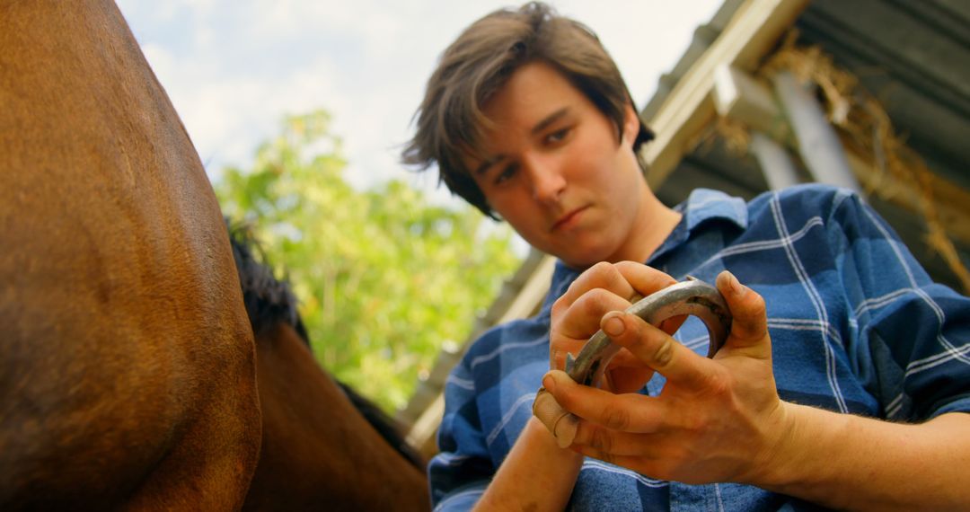 Young Farrier Preparing Horse Shoe Outdoors on Countryside Farm - Free Images, Stock Photos and Pictures on Pikwizard.com