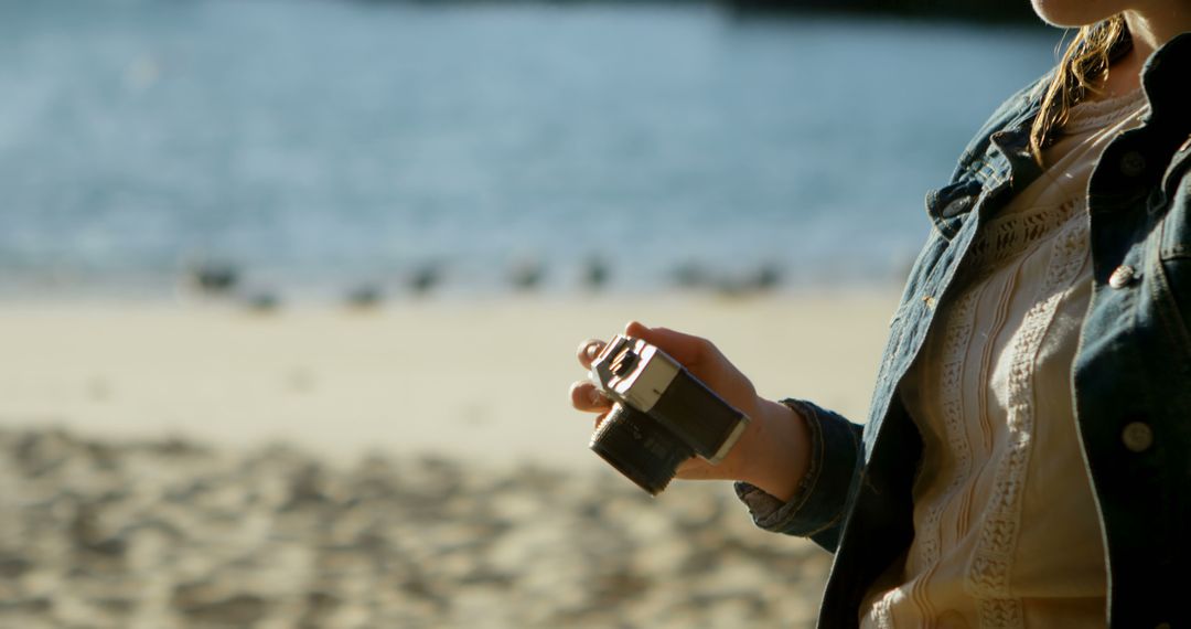 Woman Holding Vintage Camera on Sandy Beach - Free Images, Stock Photos and Pictures on Pikwizard.com