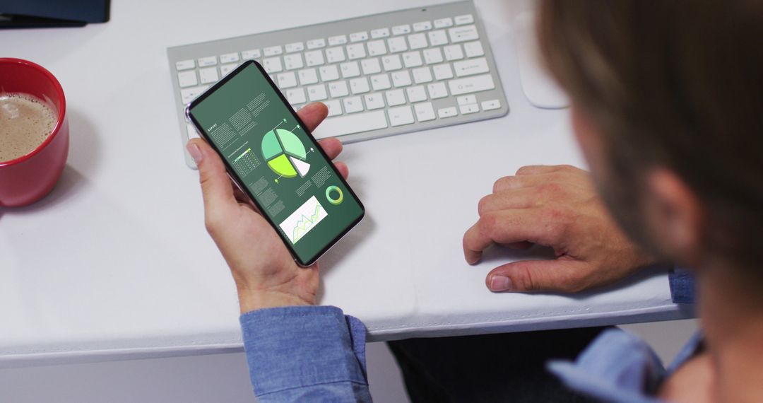 Man Analyzing Data on Smartphone at Office Desk