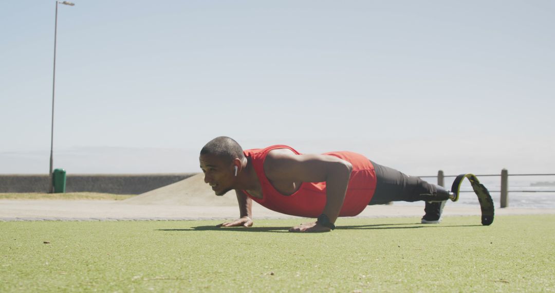 Man with prosthetic leg doing push-ups on outdoor grass surface - Free Images, Stock Photos and Pictures on Pikwizard.com