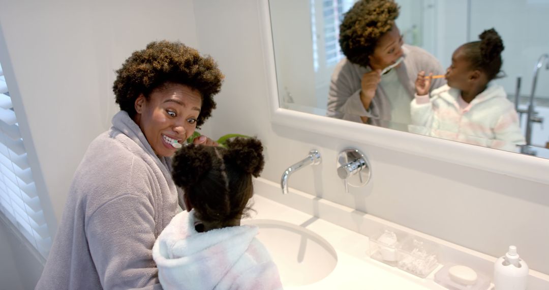 Happy African American Mother and Daughter Brushing Teeth Together in Sunny Bathroom - Free Images, Stock Photos and Pictures on Pikwizard.com