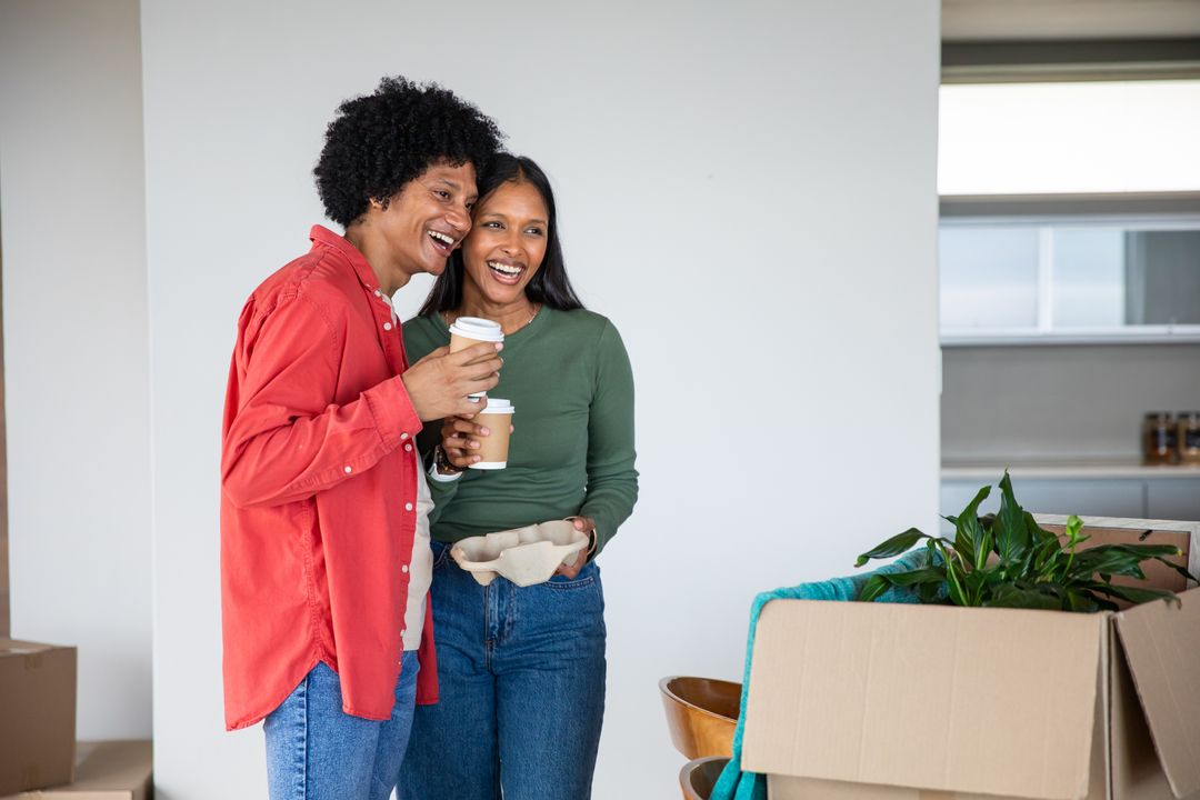 Couple Laughing While Unpacking and Drinking Coffee at New Home