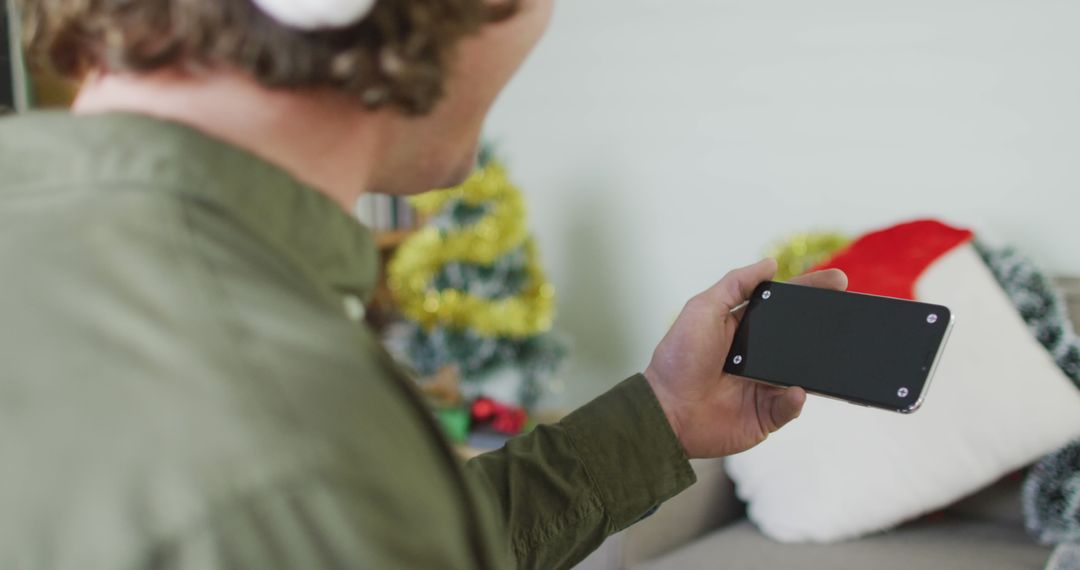 Person Holding Smartphone With Blank Screen Near Festive Decorations - Free Images, Stock Photos and Pictures on Pikwizard.com