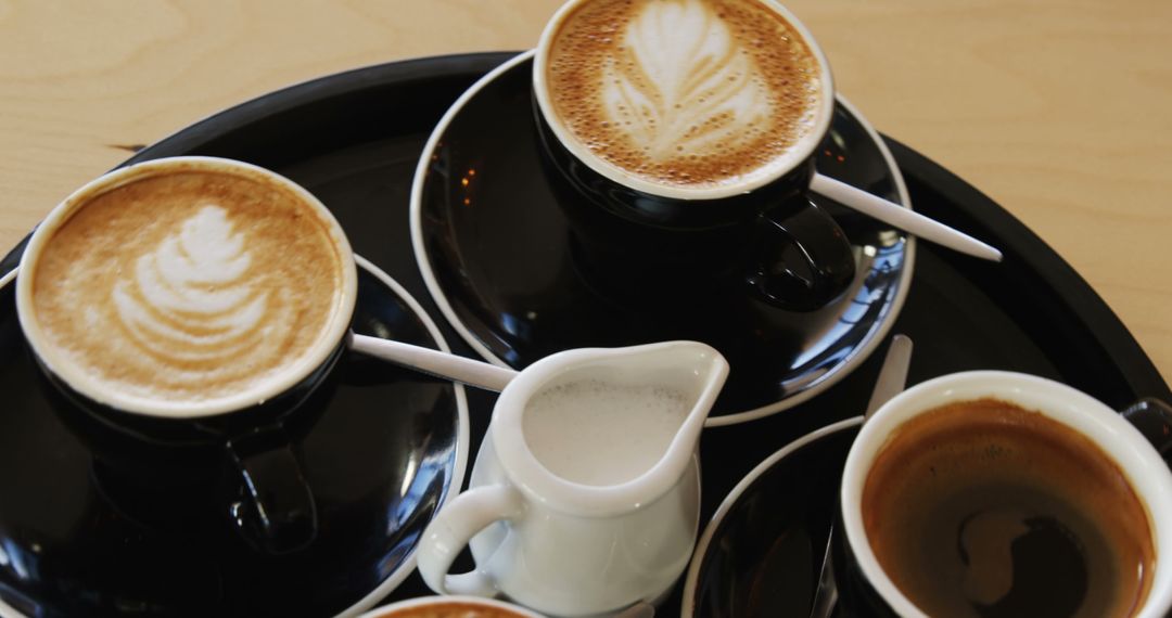 Various Lattes and Coffees on a Tray with Creamer - Free Images, Stock Photos and Pictures on Pikwizard.com