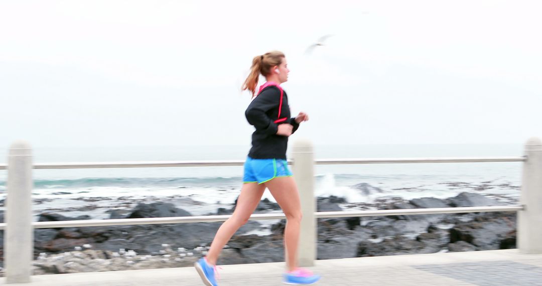 A young Caucasian woman is jogging along a seaside promenade, with copy space - Free Images, Stock Photos and Pictures on Pikwizard.com