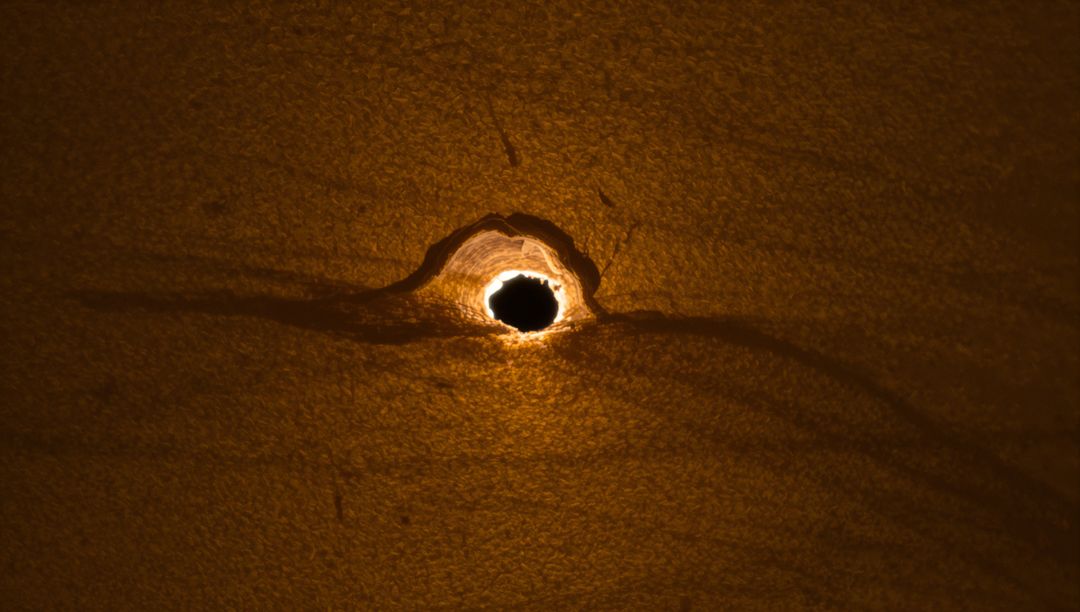 Burned Paper Puncture with Glowing Halo Macro Texture Revealing Torn Fibers and Grain