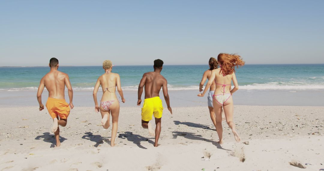 Group of Friends Running Towards Ocean on Sunny Beach Day - Free Images, Stock Photos and Pictures on Pikwizard.com