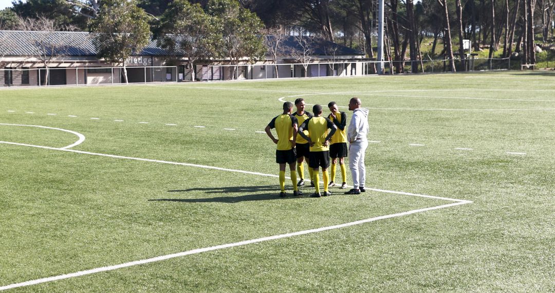 Soccer Coach Diagramming Plays with Team on Field