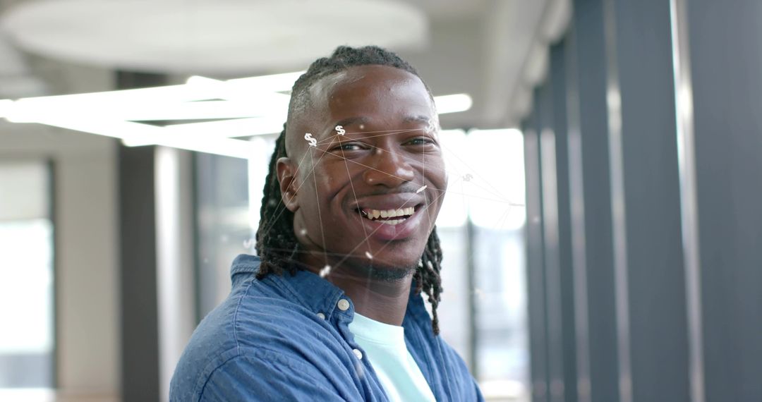 Smiling professional standing in modern office corridor with denim shirt and tech overlay