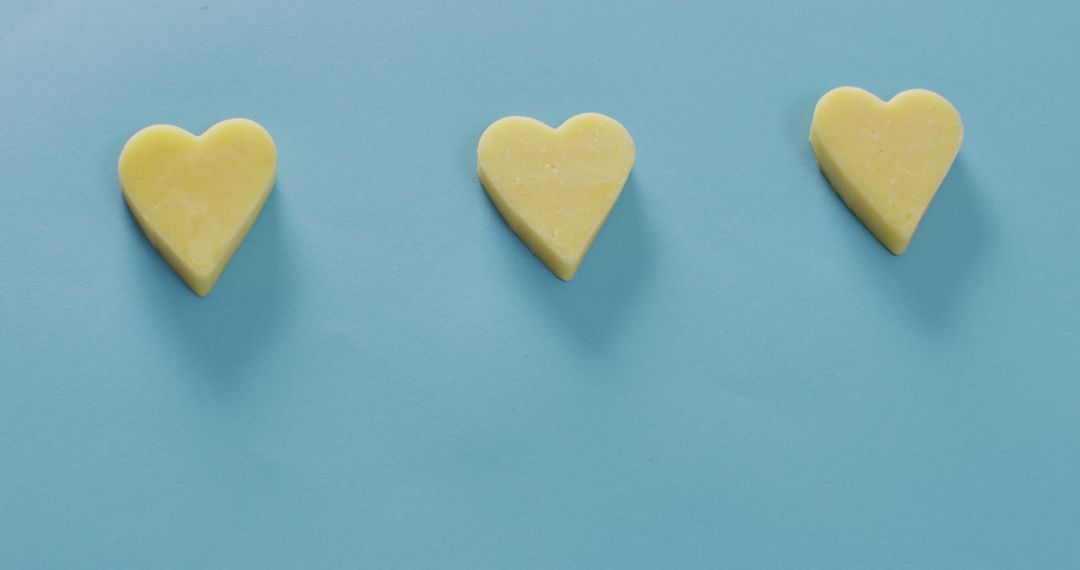 Three Yellow Heart-Shaped Butter Placed on Light Blue Background - Free Images, Stock Photos and Pictures on Pikwizard.com