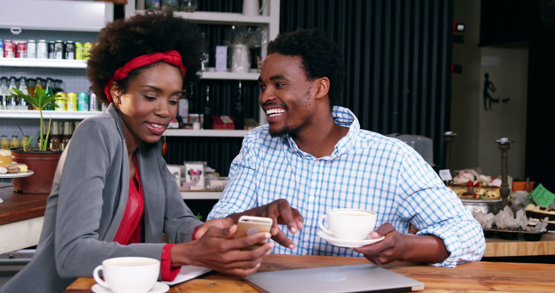 Smiling Couple Enjoying Coffee and Using Smartphone at Cozy Cafe - Free Images, Stock Photos and Pictures on Pikwizard.com