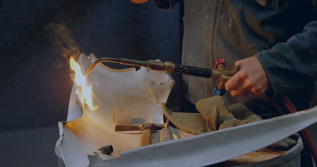 Metalworker Uses Blowtorch to Shape Metal Panel in Workshop