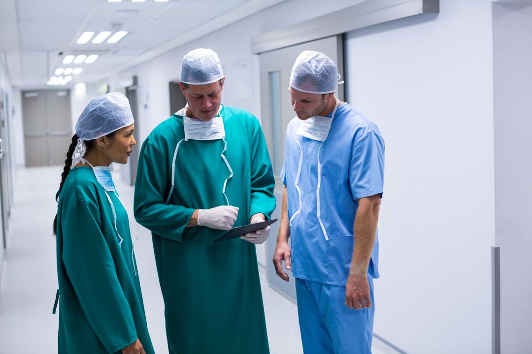 Surgeons Discussing Patient Information on Digital Tablet in Hospital Corridor - Free Images, Stock Photos and Pictures on Pikwizard.com