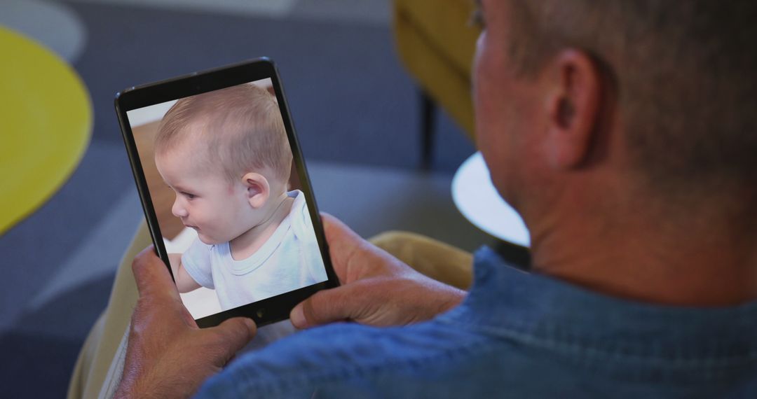 Man Viewing Baby's Photo on Tablet, Nostalgic Moment - Free Images, Stock Photos and Pictures on Pikwizard.com