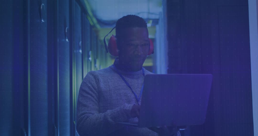 Technician in Data Center Using Laptop with Digital Data Overlay